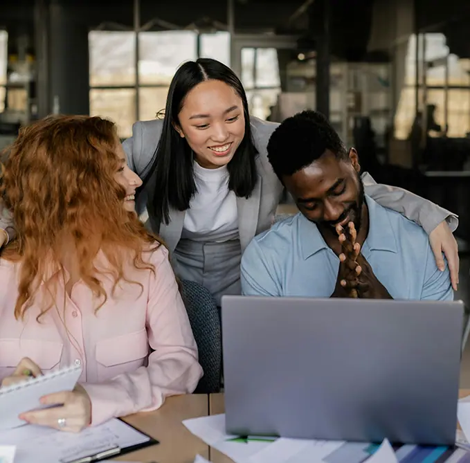 Three people having fun while discussing in front of their laptop
